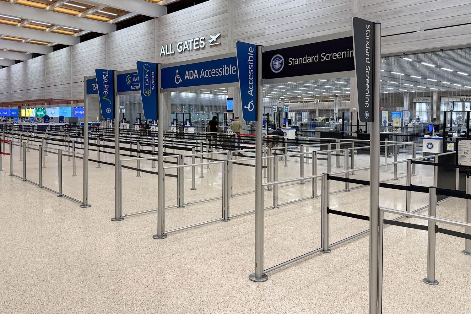 Overhead signs and banners on tall partition posts mark the entrance to the security queue at Kansas City International Airport.