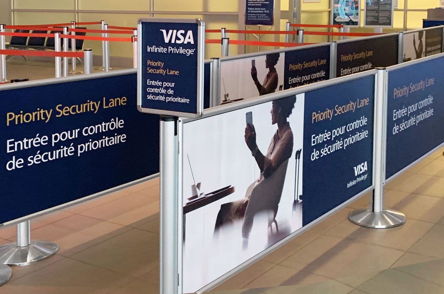 Post and Panel barriers with printed priority lane graphics organize the security queue at Billy Bishop Toronto City Airport.