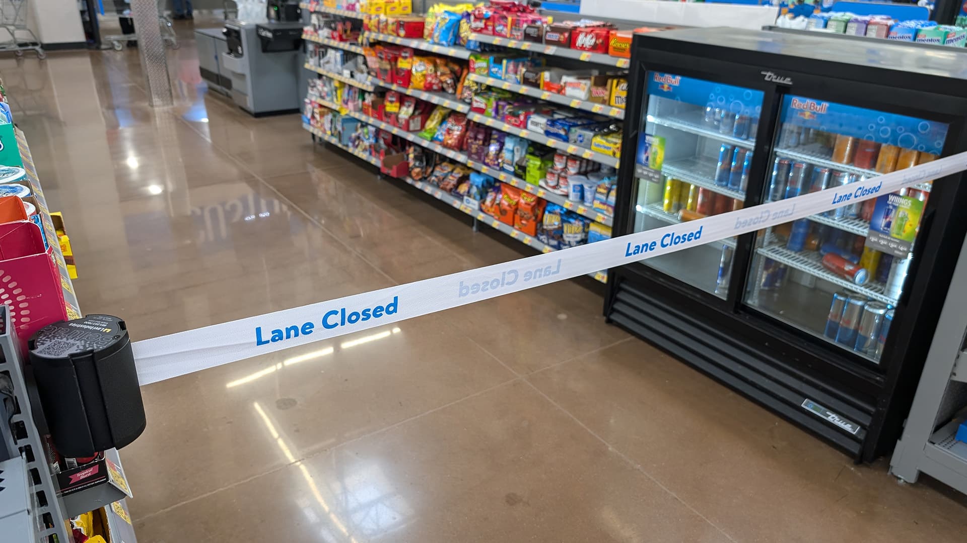 A magnetic retractable belt safety barrier closes a checkout lane at a Walmart store.
