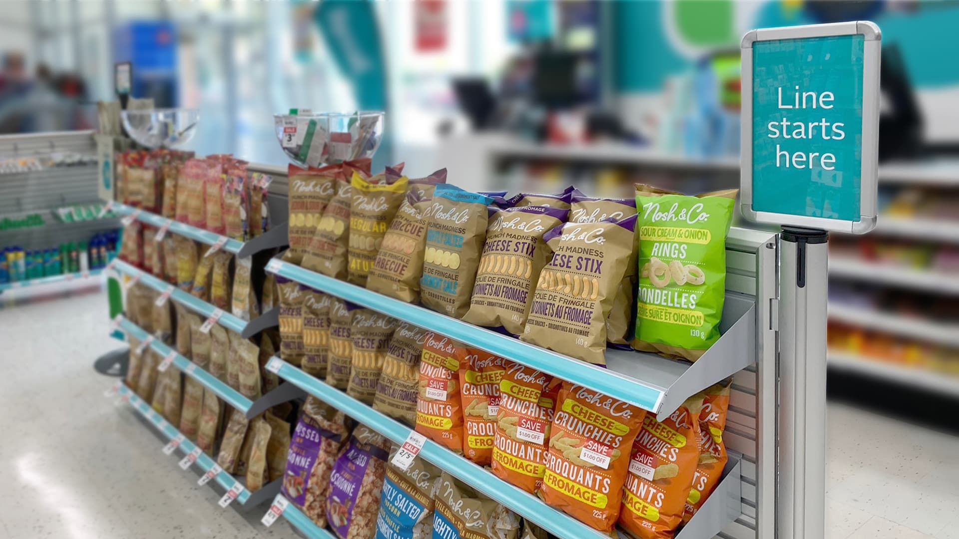 NeXtrac slatwall shelves merchandise snacks along the checkout queue at a Rexall drugstore.