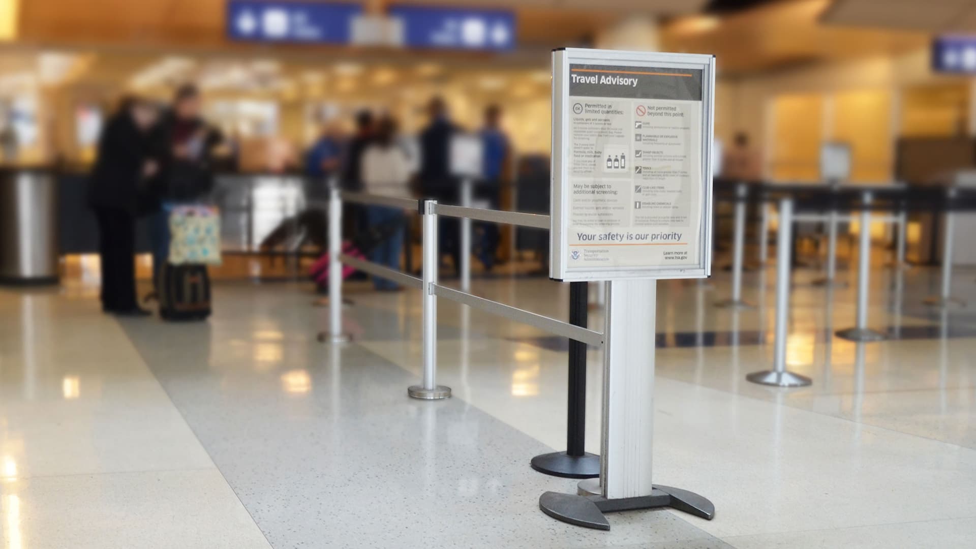 A DirecTrac sign stand directs passengers at the entrance to an airport security queue.