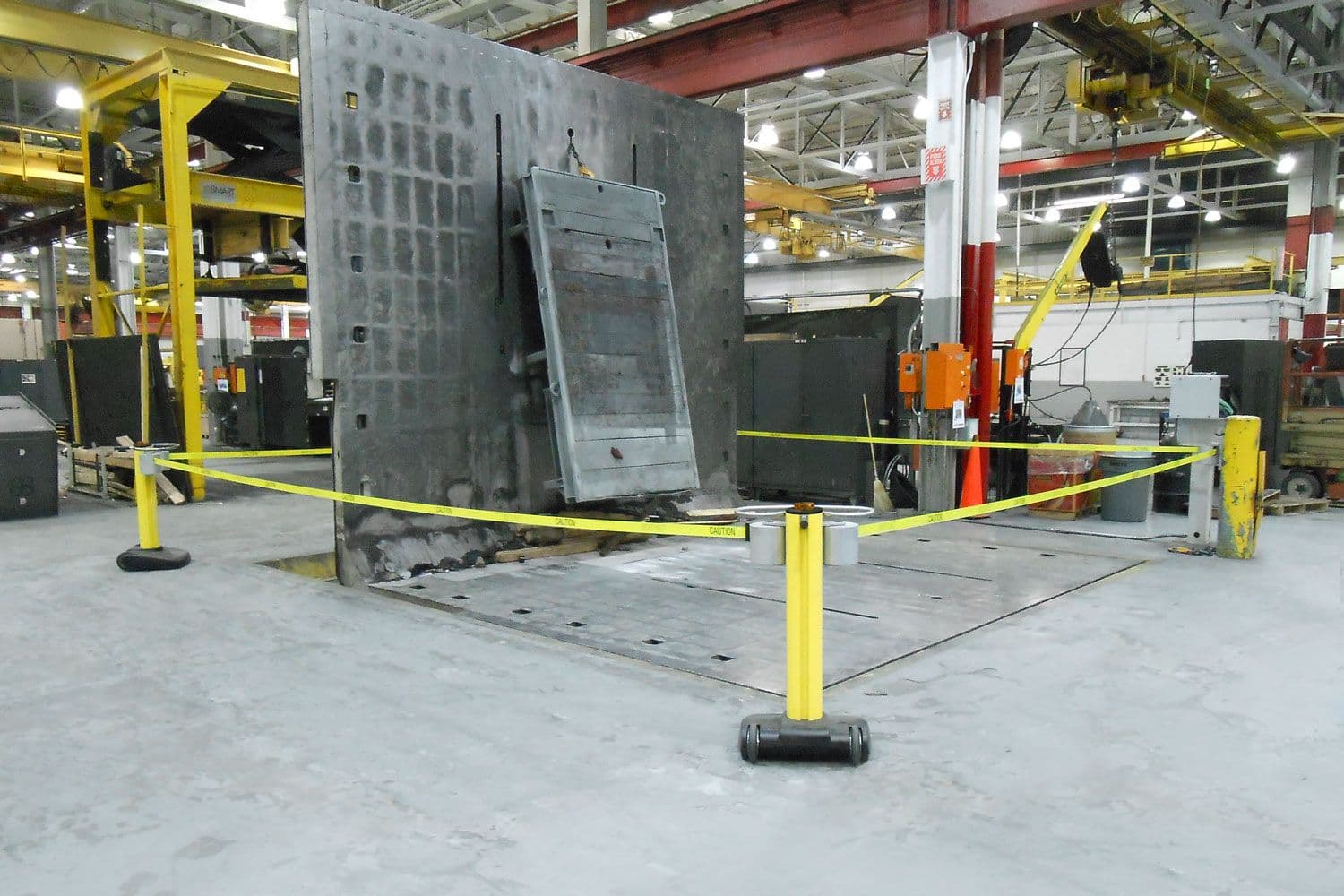 A JetTrac retractable belt barrier guards a sheet metal press on a factory floor.