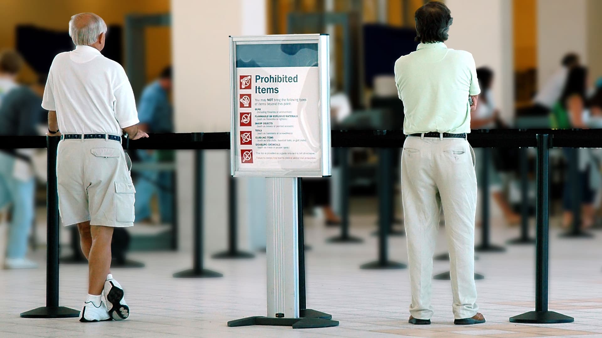 A DirecTrac sign stand with printed rules directs travelers into a TSA security queue.