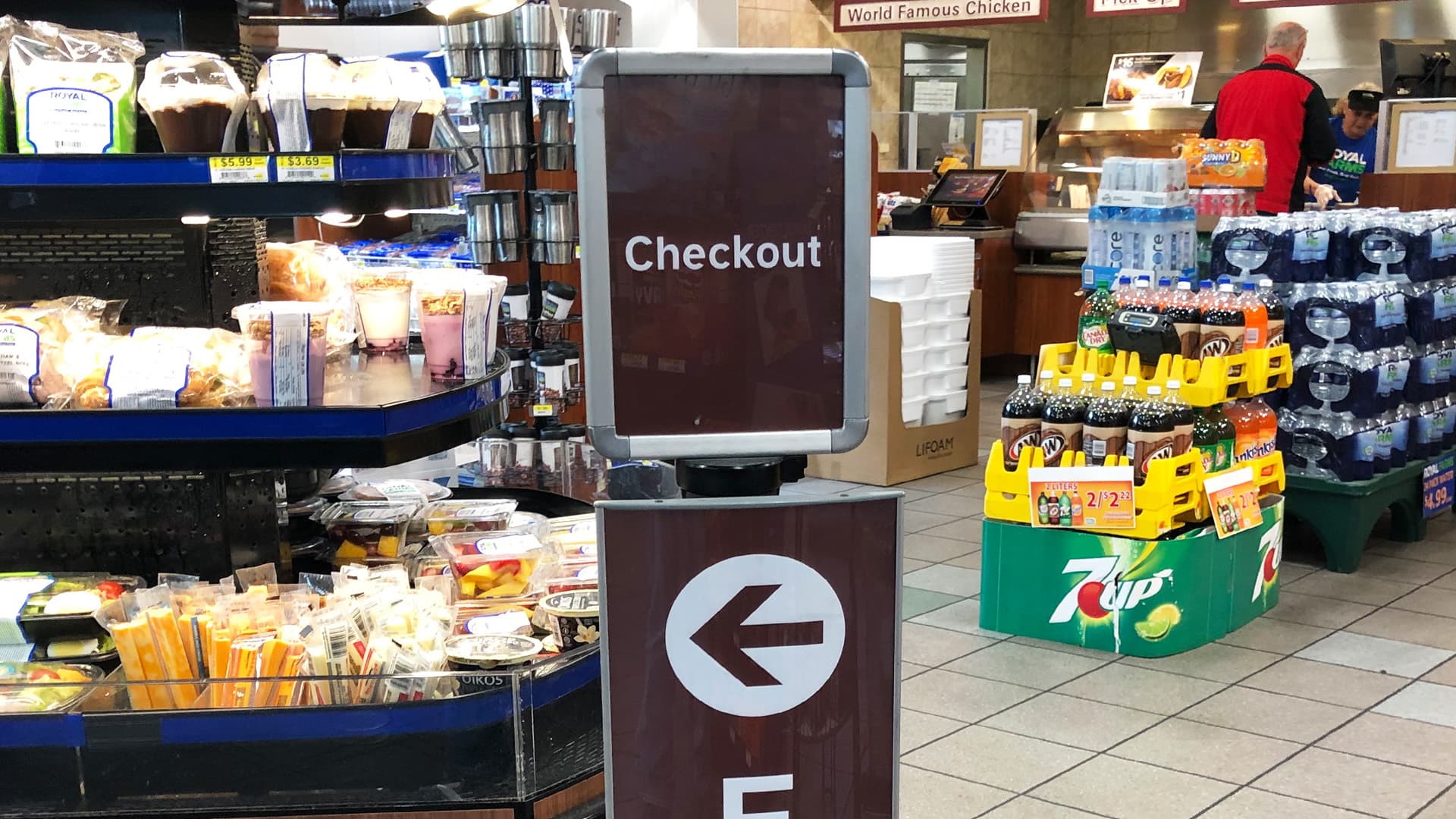 Beltrac retractable belt stanchions with a post-top sign guide customers to the checkout at a Huck's convenience store.