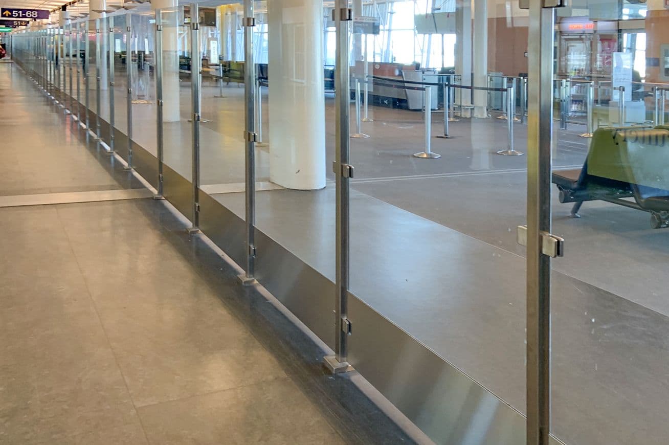 An Architectural Partition Wall with glass panels divides the passenger area at Montreal International Airport.
