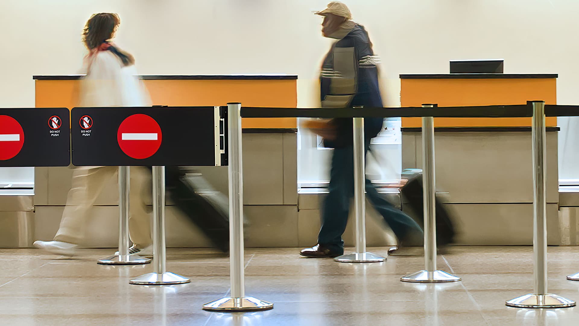 A Beltrac stanchion swing gate marks the exit point of a security queue inside an airport terminal.