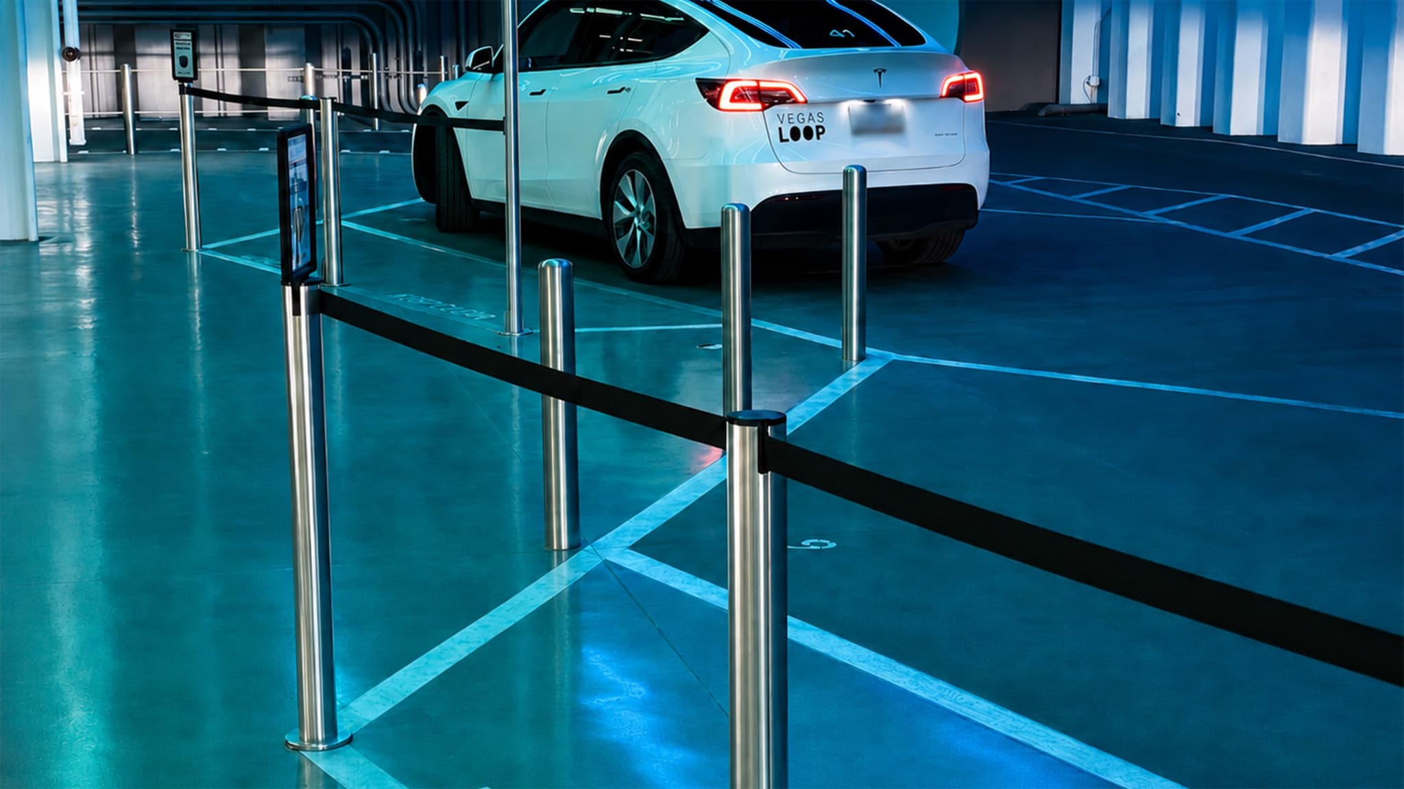 Beltrac stanchions with post-top signs guide riders to the Tesla loading curb at the Vegas Loop station.