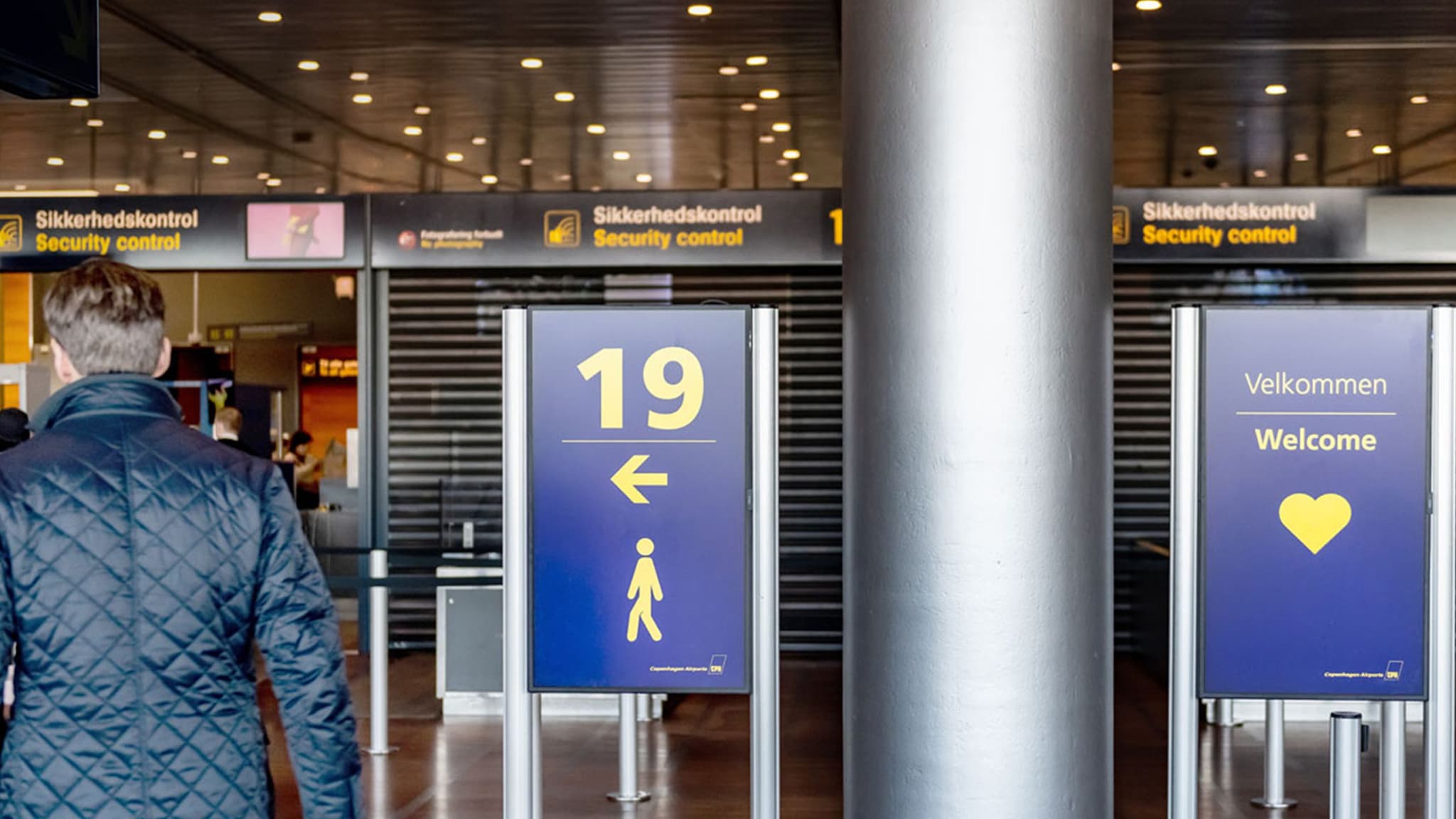 Intelligent Queuing digital signage directs passengers to the security checkpoint at an airport terminal.