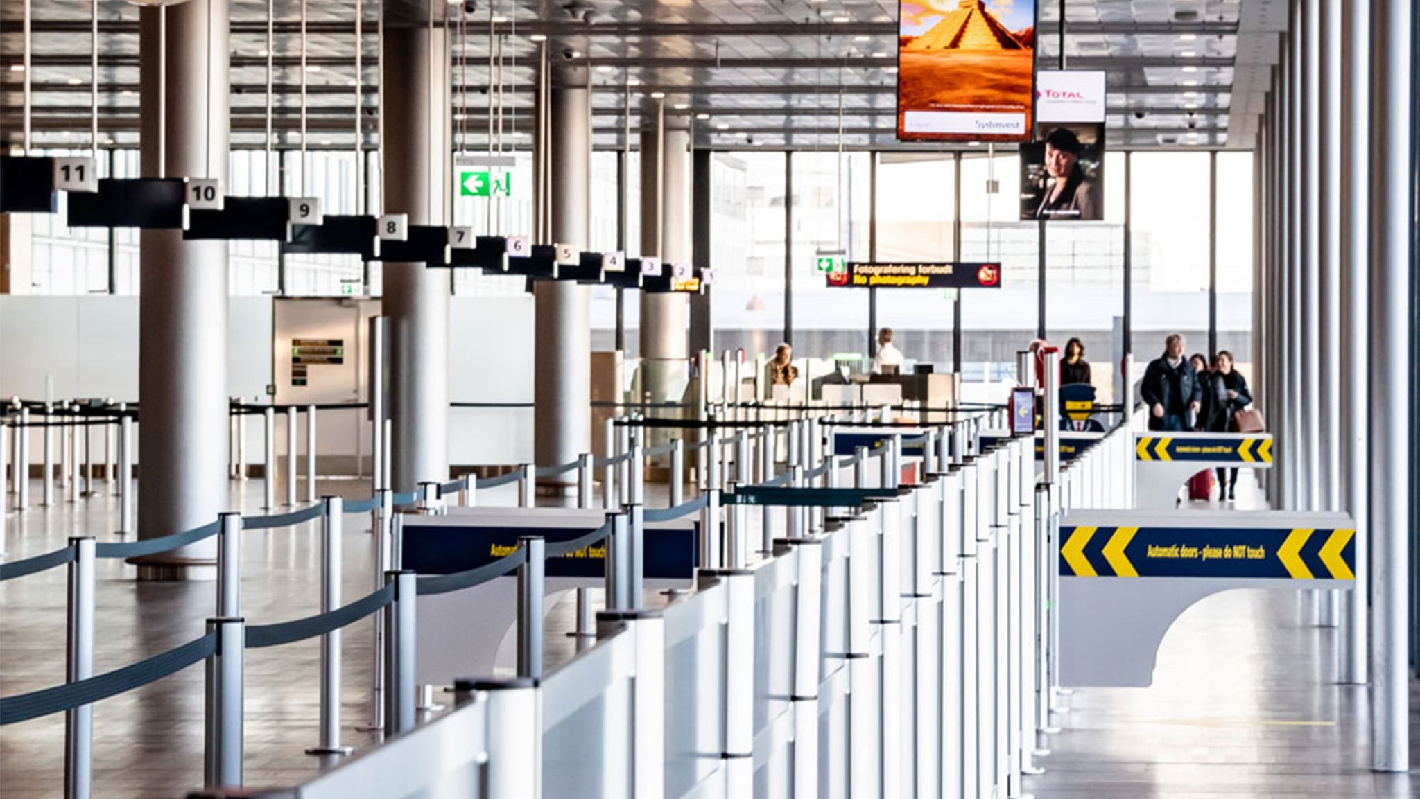 Automated gates open for passengers at the entrance to an Intelligent Queuing airport security lane.