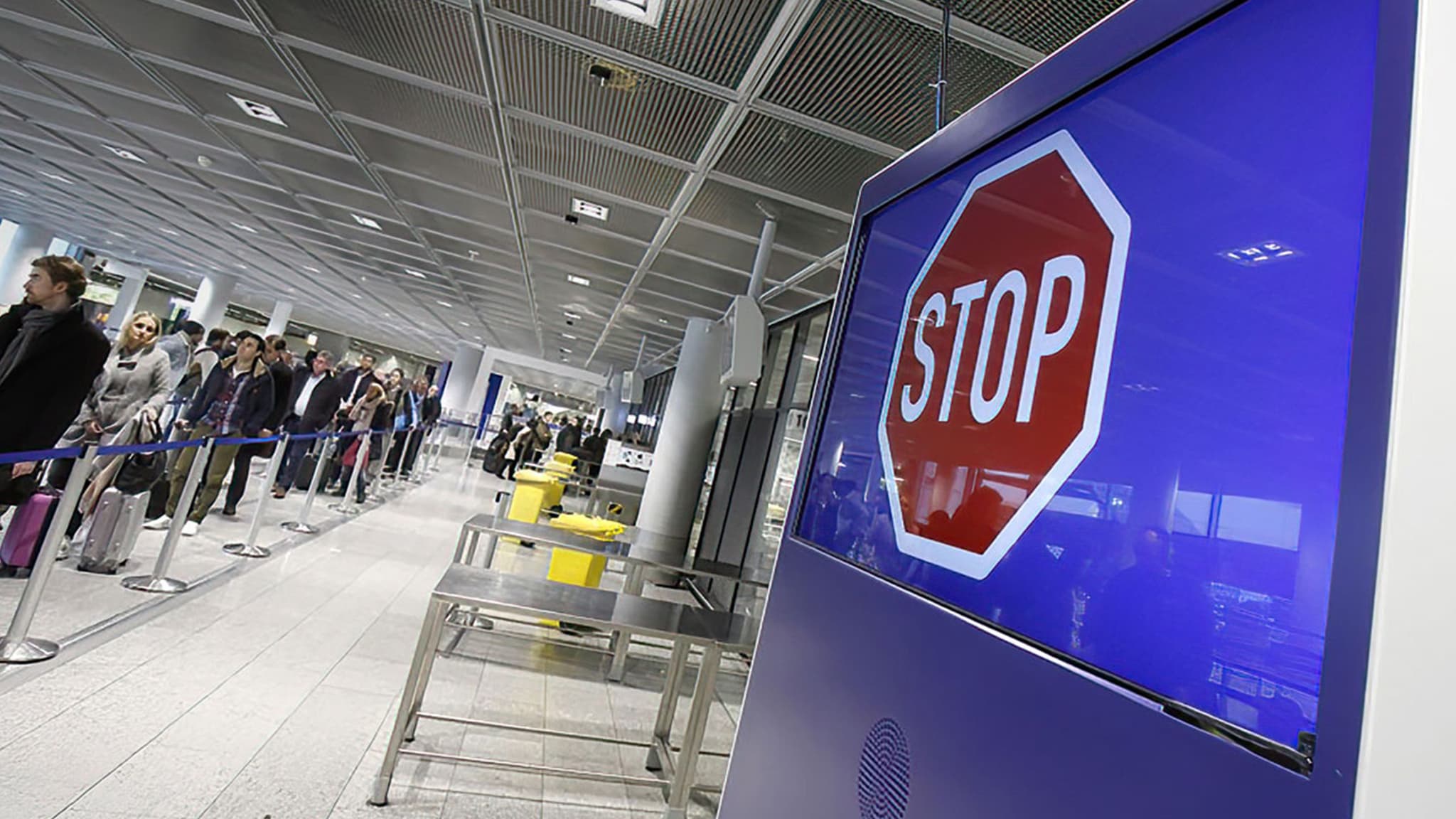 An electronic queuing system with overhead displays guides passengers through an airport security checkpoint.