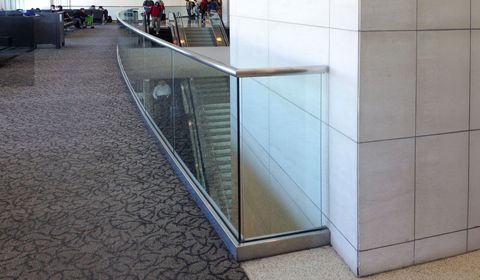Aluminum shoe moulding and glass cap rail protect a stairwell in a building